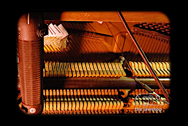 Still image of a microphone attached to a piano from the Prepared Piano video by the Jawshop Adventure Recording Studios.
