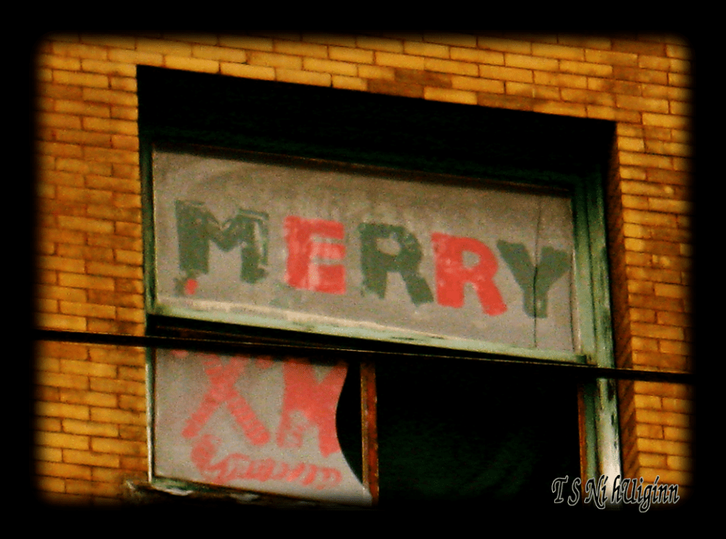 A photograph taken by TS Ni hUiggin of 'Merry X' on a broken window on East Hastings, Van BC.